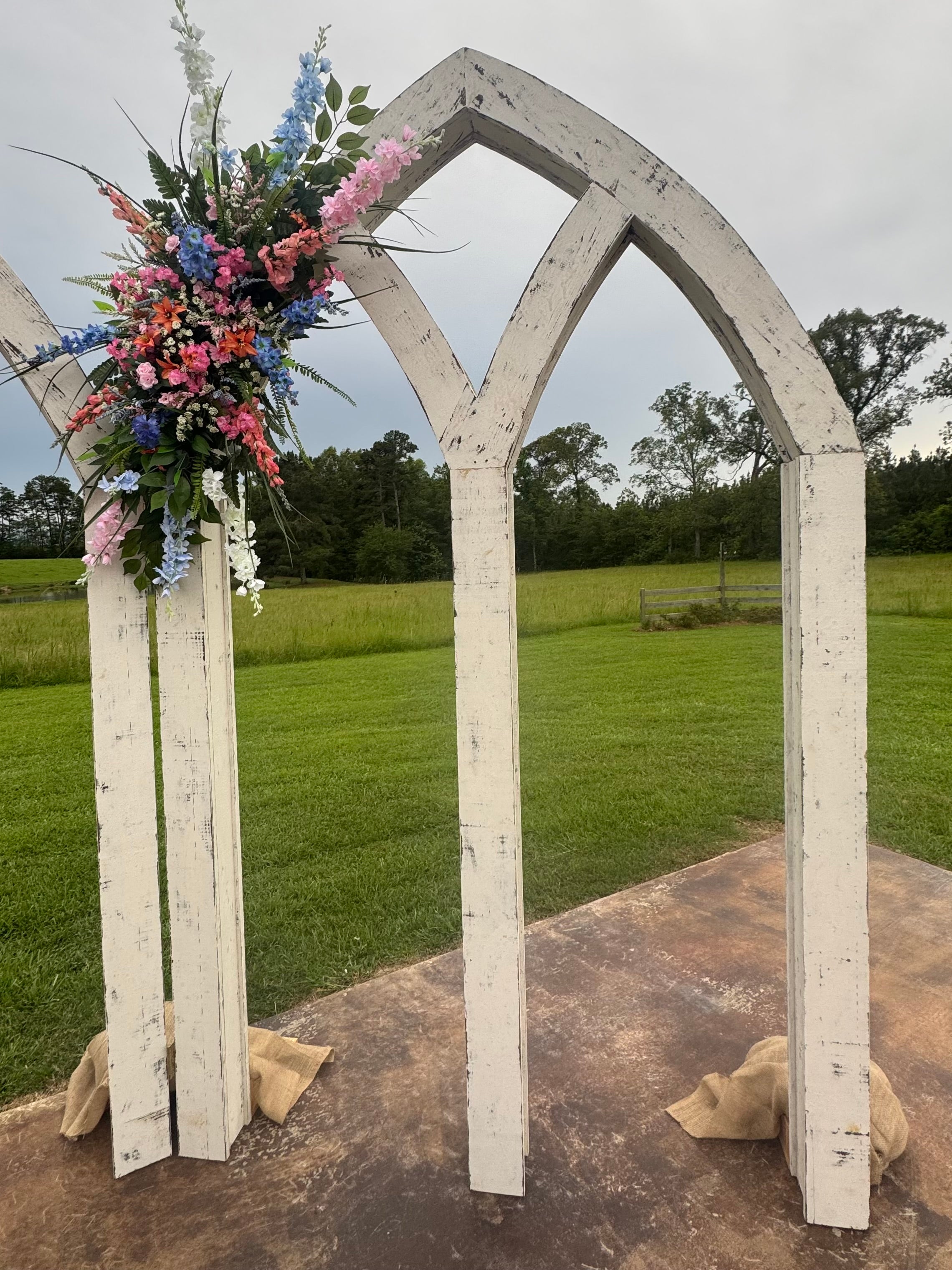 Custom made wooden wedding arch with floral decorations in an outdoor setting.